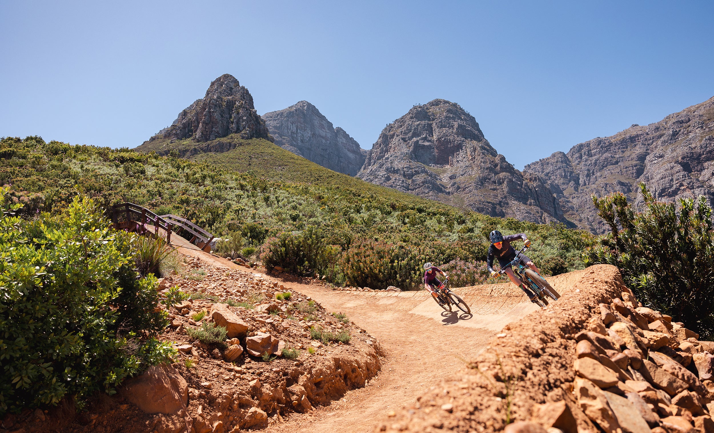 Twee mountainbikers rijden een flowtrail tussen de bergen van de Westkaap